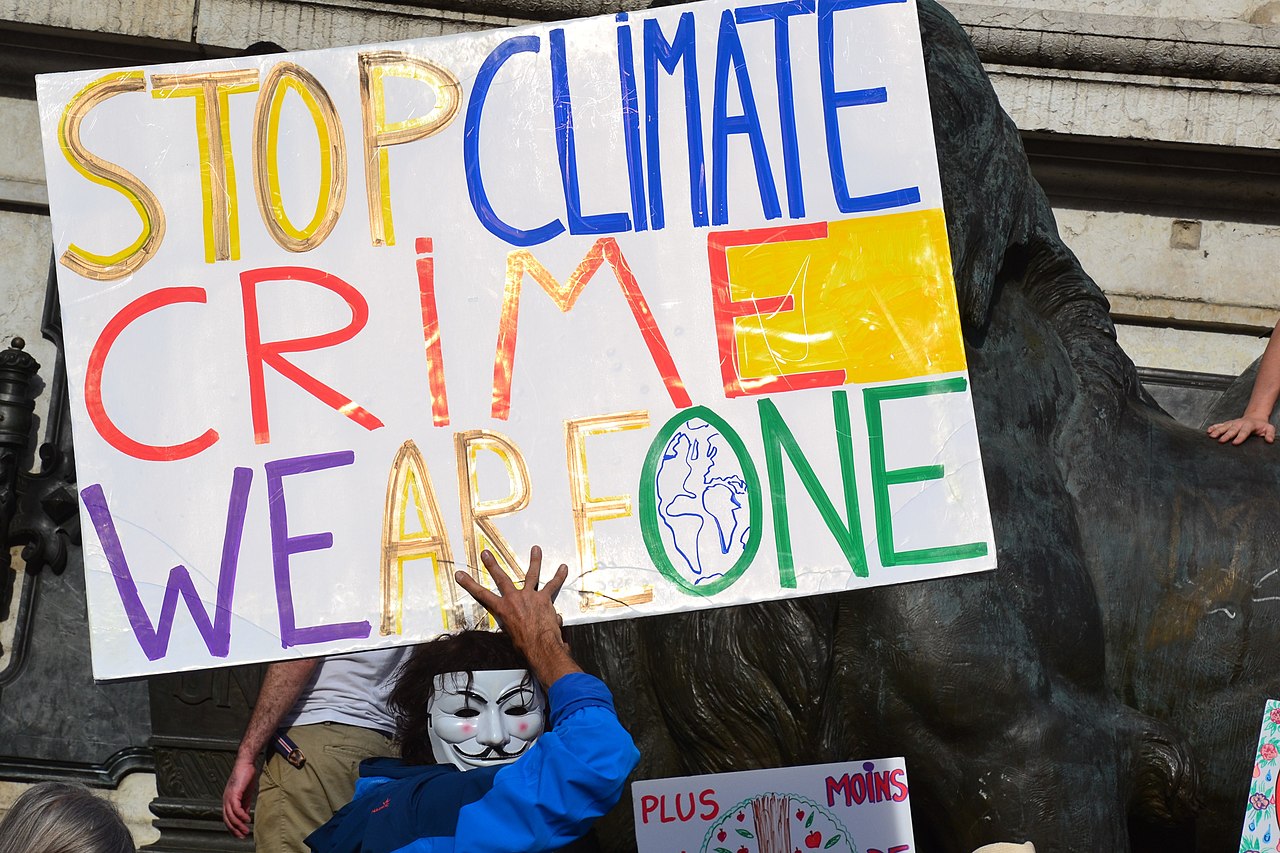 protester holding sign that reads stop climate crime, we are one
